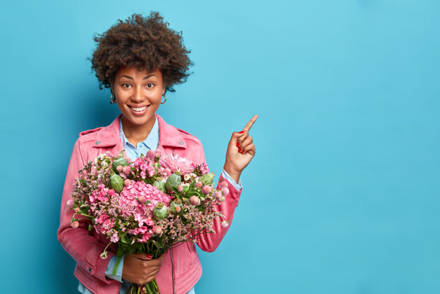 情感积极的非洲裔美国妇女 带着牙齿般的微笑 手持一束鲜花花欢呼花
