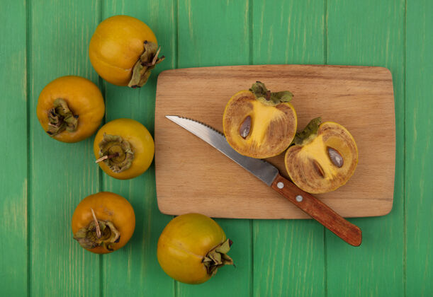 木头顶视图橙色圆形柿子水果在一个木制的厨房板与刀在一个绿色的木桌上新鲜木板景观