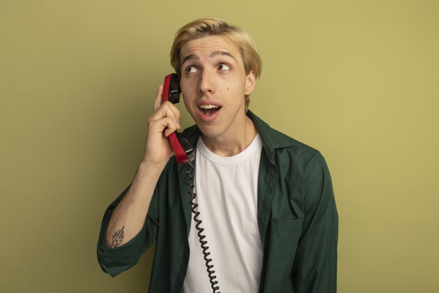请高兴地看着身边穿着绿色t恤的金发小伙子在电话里讲话年轻金发男人