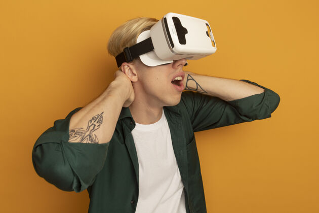 虚拟现实惊讶地看着身边穿着绿色t恤和vr头戴式耳机的金发小伙科技虚拟现实年轻