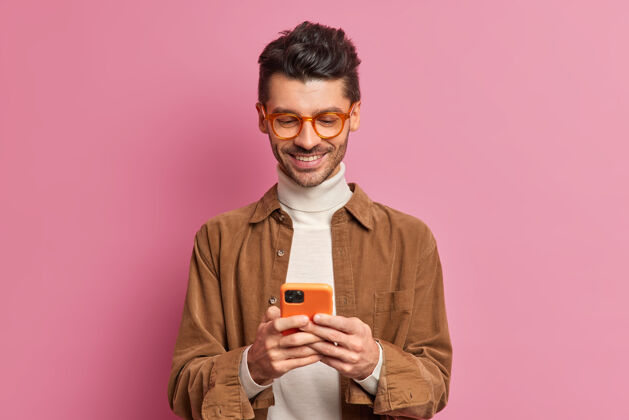 微笑欧洲男子博客在智能手机上输入短信的摄影棚照片 笑容可掬聊天打字年轻