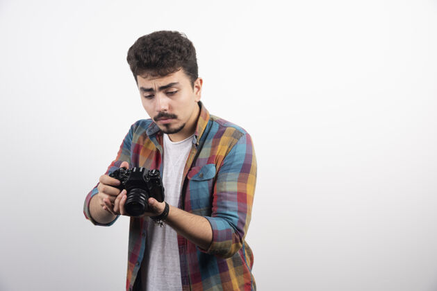 男性照片看着他的相机思考着聪明年轻摄影