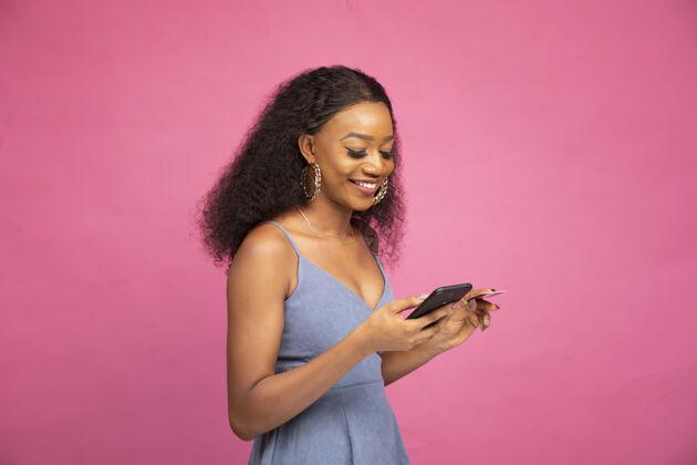 电话一位年轻的非洲女性使用智能手机和信用卡在线购物的侧视图电子商务在线支付