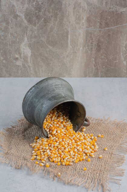 烹饪玉米从一个小金属罐里喷溅出来 落在大理石表面的一块布上罐子面粉农业