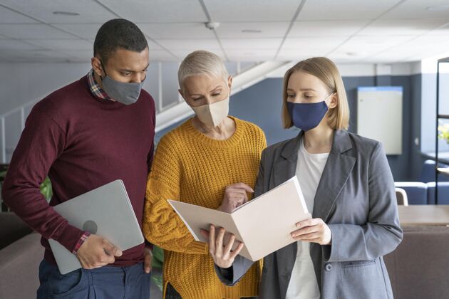 人上班的人戴着医用口罩工作场所社会距离同事