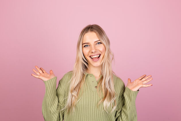健康漂亮的欧洲女人在粉红色的墙上穿着休闲针织毛衣信心时尚积极