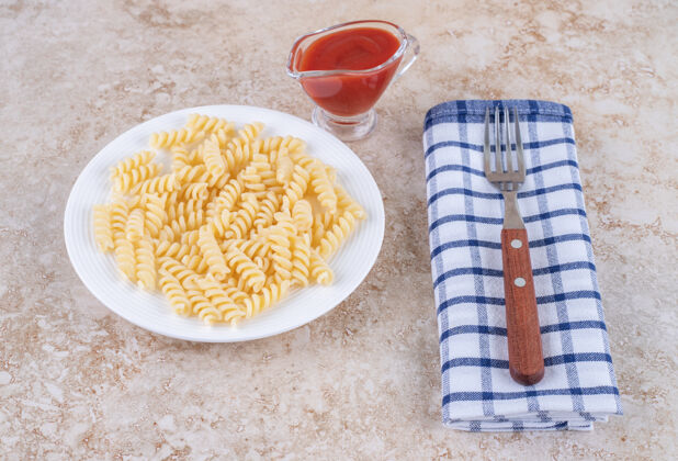 美味一杯番茄酱 配上通心粉和叉子 放在大理石表面的毛巾上面食通心粉晚餐