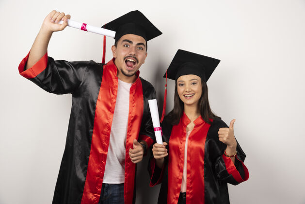 女有文凭的应届毕业生对白人竖起大拇指年轻成功站