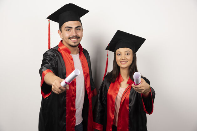 长袍应届毕业生穿着长袍 拿着白色的毕业证书摆姿势帽子成功年轻