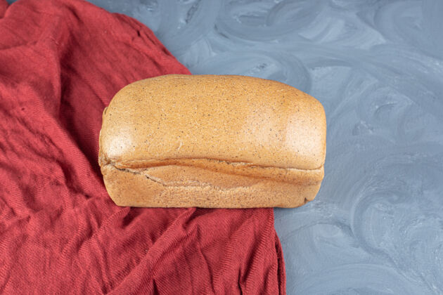 烘焙在大理石表面的红色桌布上放一块面包松脆面包美味