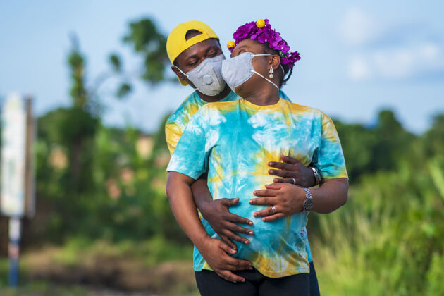 安全一对快乐的非洲裔美国夫妇和一位戴着防护面罩的孕妇拥抱并摆姿势女性男性爱