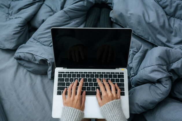 温和在寒冷的日子里 在床上用笔记本电脑工作的女人休闲放松轻松