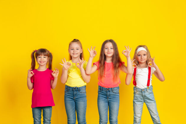 团结快乐的孩子们一起在黄色的墙上玩耍和玩耍跑步女孩表情