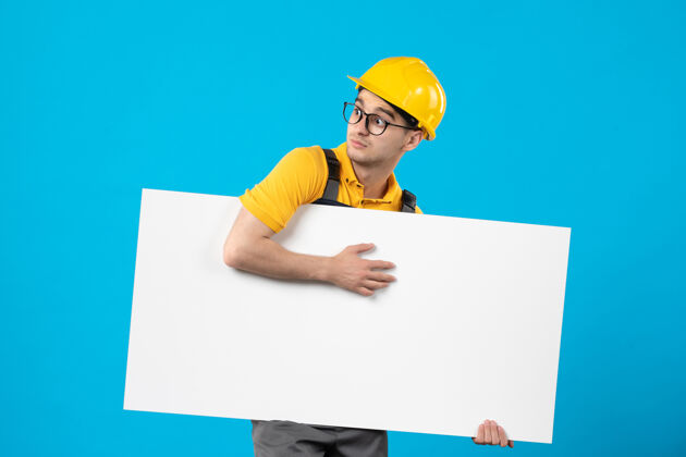 工程师前视图男性建筑工人穿着黄色制服 蓝色平面图工作表面头盔