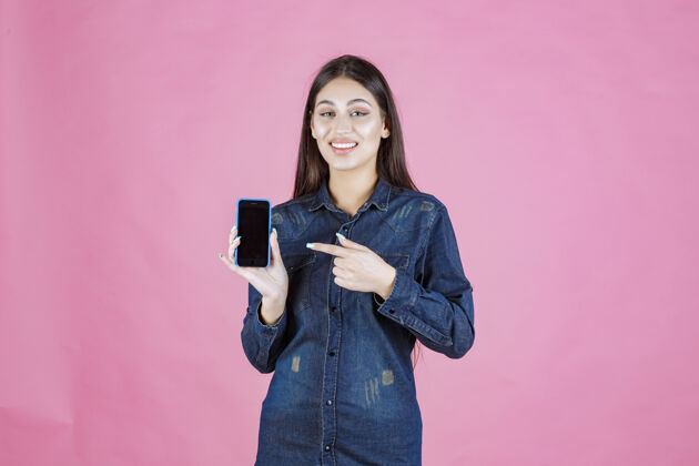 晋升女孩拿着一部全新的智能手机指着它女人休闲科技