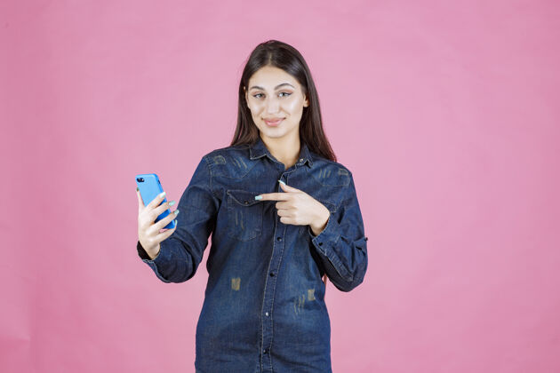 科技女孩拿着一部全新的智能手机指着它女人人类女性