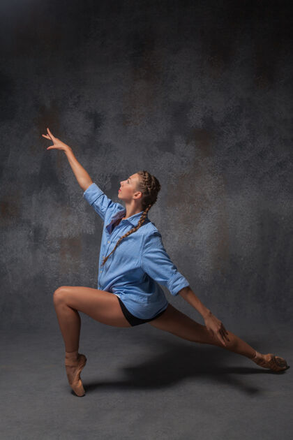 酷年轻漂亮的现代风格舞者穿着蓝色衬衫 在灰色背景下摆姿势优雅表演灵活