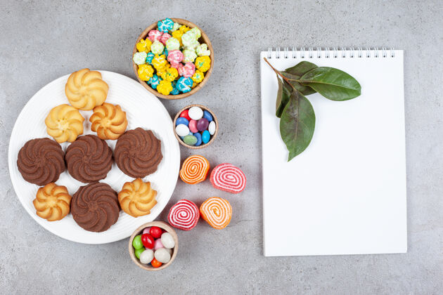 糕点各式各样的饼干 糖果和marmelade旁边的白板和大理石背景上的叶子高品质的照片美味果酱糖果