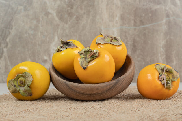 粗麻布一堆熟了的美味柿子放在木碗里四季生的天然