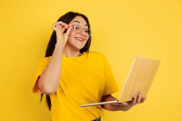 面部黄色墙上隔离着笔记本电脑的年轻女子的画像人秀工作