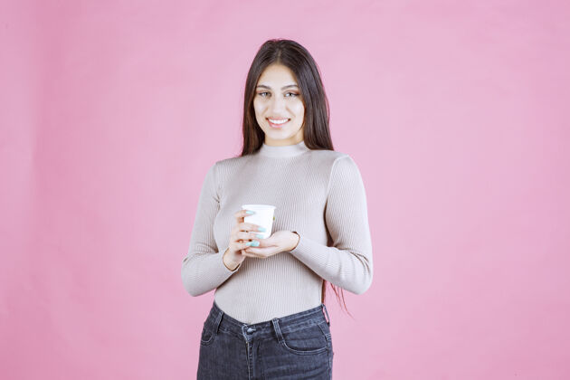 广告女孩拿着一个白色的一次性咖啡杯 推销它或闻到新鲜的咖啡商业女人人
