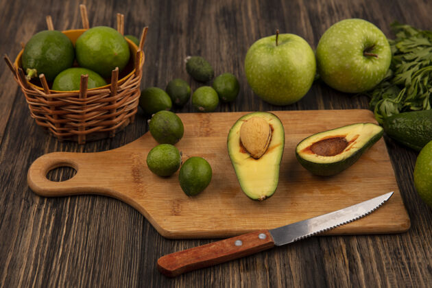 小吃木制厨房板上健康鳄梨的俯视图 木桶上放着小刀和酸橙 木桶上放着苹果和欧芹顶膳食苹果