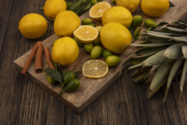 板顶视图柑橘类水果 如金盏花和柠檬肉桂棒上的木制厨房板与菠萝上的木制背景水平柠檬柑橘