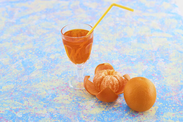 鸡尾酒一杯橘子汁 周围有柑桔 蓝色背景 高质量的照片新鲜热提神