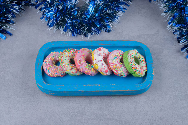 拼盘在大理石表面的蓝色盘子上放着一排甜甜圈划船糖果烘焙食品