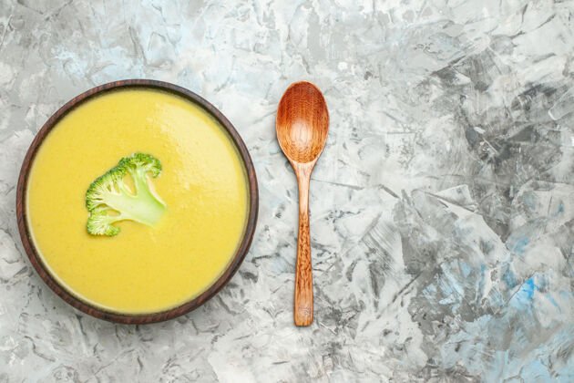 西兰花汤俯瞰图奶油西兰花汤在一个棕色的碗和勺子在灰色的桌子上头顶餐具盘子