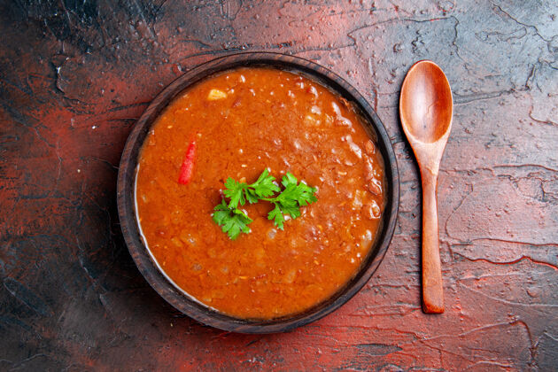 热的特写镜头的经典番茄汤在一个棕色的碗和勺子上混合颜色的表晚餐汤碗混合物