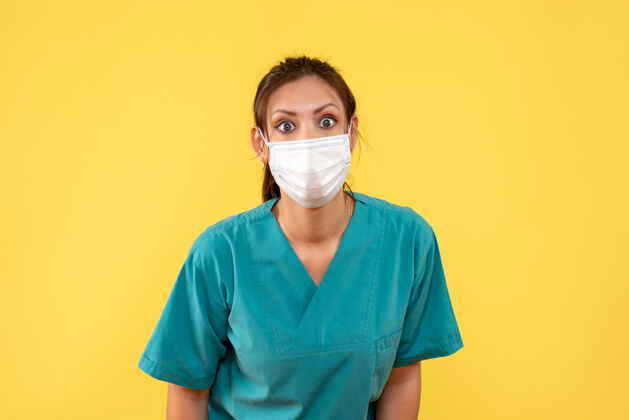 专业前视图黄色背景上穿着医用衬衫和面罩的女医生医疗面具衬衫