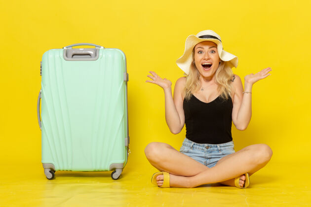 感情正面图年轻的女性坐在她的绿色袋子上 感觉快乐的黄墙旅行度假旅行女孩白色家电年轻洗衣机