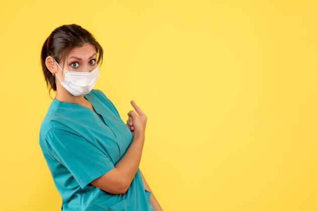健康前视图黄色背景上穿着医用衬衫和面罩的女医生支持护士女医生