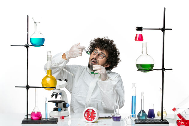 实验正面图身着特殊套装的年轻男性科学家在白墙上注射和溶解实验室实验室化学