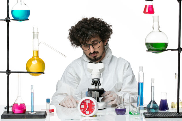 特殊正面图穿着白色特别套装的年轻男科学家正在尝试使用显微镜试试显微镜化学