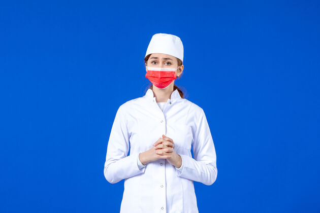 医院正面图身着医疗服的年轻护士 蓝色墙上戴着红色防护面具面罩红蓝