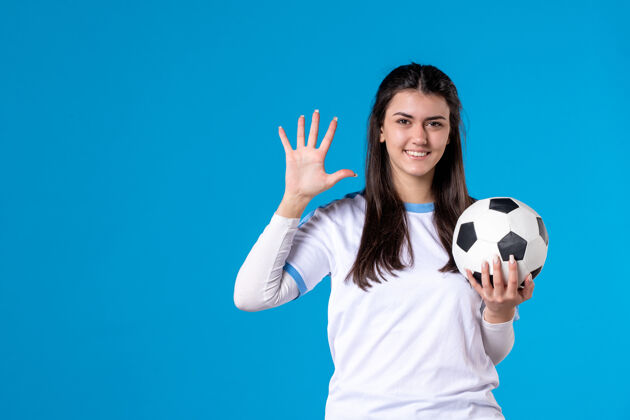 青年前视图：蓝色墙上有足球的年轻女性人足球足球