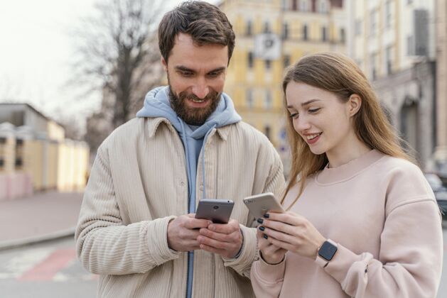 情侣笑脸情侣在城市户外使用智能手机女性移动城市