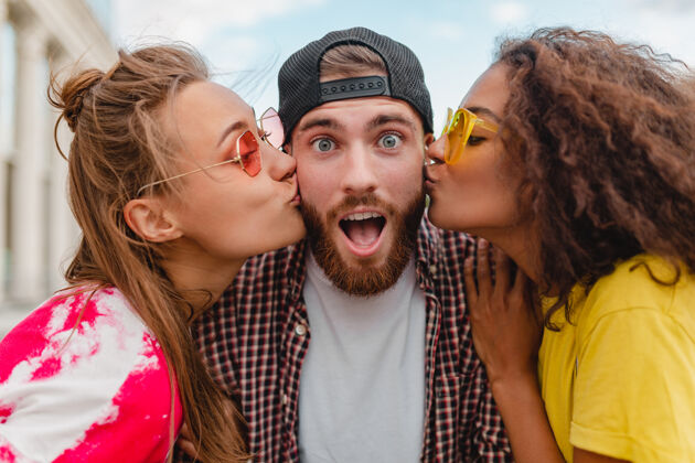三两个女人亲吻着男人 快乐兴奋的情绪 年轻的朋友们一起欢笑情绪人亲吻