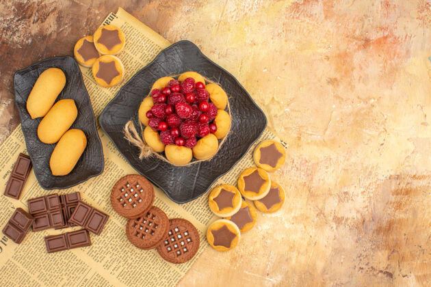 水果美味蛋糕俯视图不同的饼干放在棕色盘子上的混色桌上混合浆果胡椒