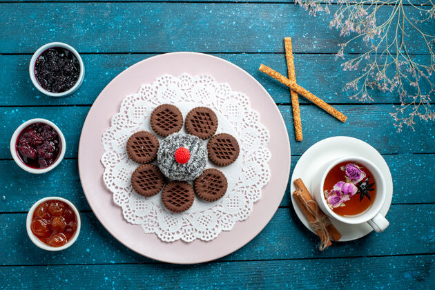 饼干俯瞰美味的巧克力饼干与果酱和一杯茶在一个蓝色的乡村办公桌饼干茶饼干甜蛋糕糖顶部巧克力餐点