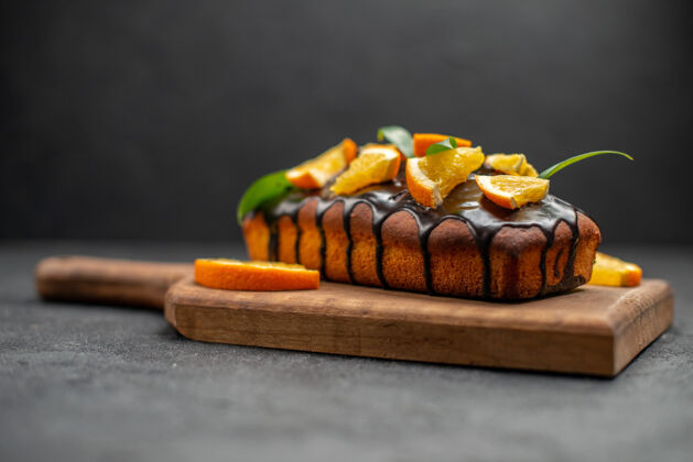 切美味的蛋糕装饰着橘子和巧克力在木制的砧板上放在黑色的桌子上小吃美味蛋糕食物