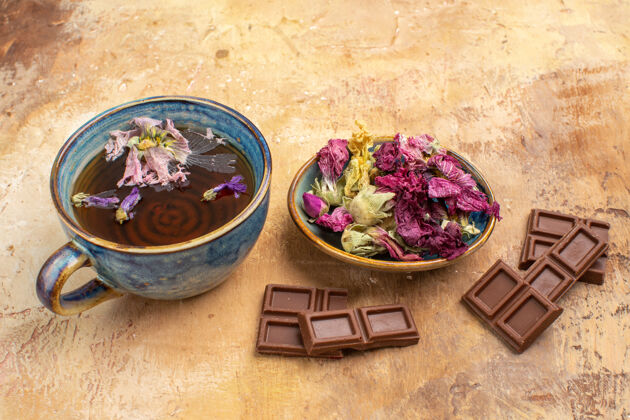 热一杯热乎乎的花草茶和巧克力的特写镜头放在五颜六色的桌子上混合封闭蔬菜