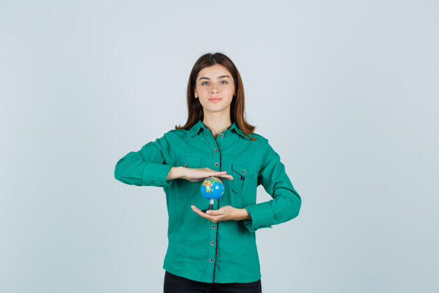 正面穿着衬衫拿着地球仪的年轻女士看起来很高兴正视图手势休闲毛衣