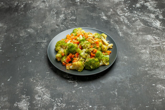西红柿灰色桌子上的黑色盘子上有西兰花和胡萝卜的健康餐的水平视图午餐花椰菜一餐
