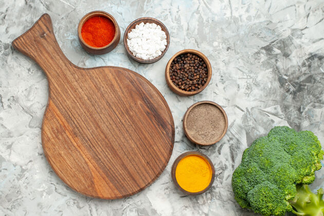 食品健康木砧板的水平视图不同的香料和西兰花放在白色的桌子上容器香料西兰花