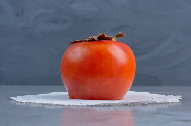 健康多汁的柿子放在大理石背景的小桌布上柿子风味新鲜