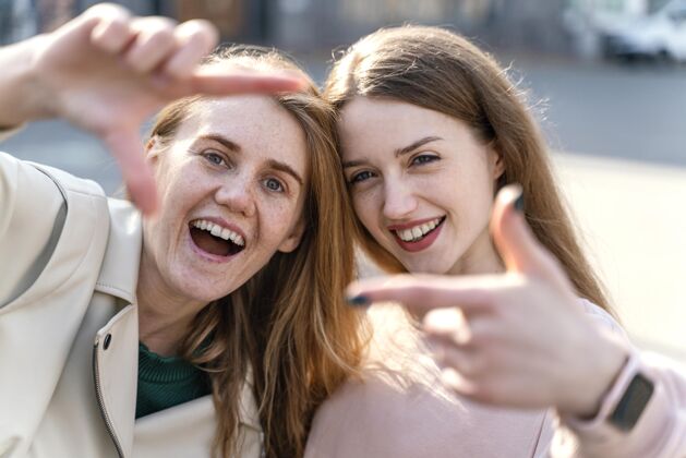 水平两个满脸笑容的女性朋友在城市户外假装自拍城市女性自拍