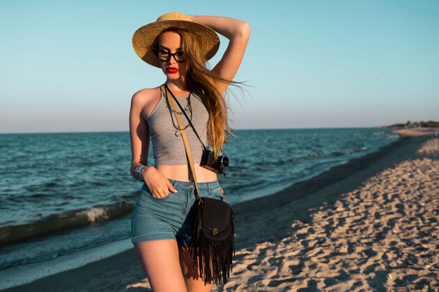 海滩美丽的金发女人戴着草帽在海边散步的户外夏日形象帽子放松海洋